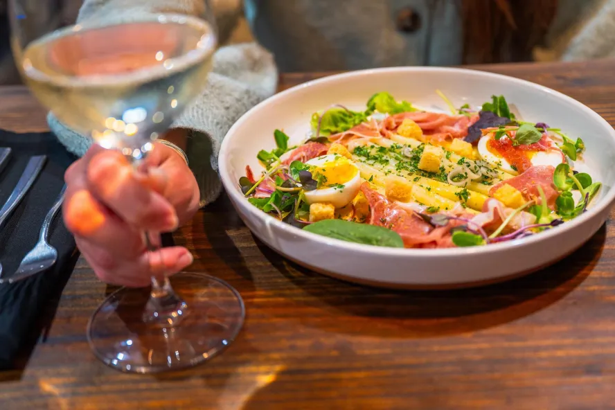 a woman having a salad and a glass of wine at The Restorative in Dunedin