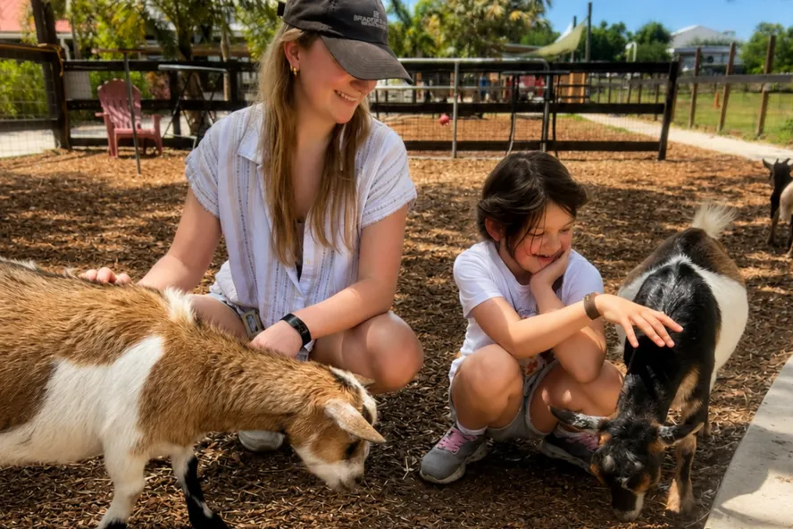 A woman and girl pet two playful goats at DK Farms & Gardens in Largo, Florida