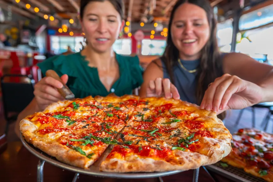 two women get ready to dig into a margarita pizza at Nona Slice House in Safety Harbor