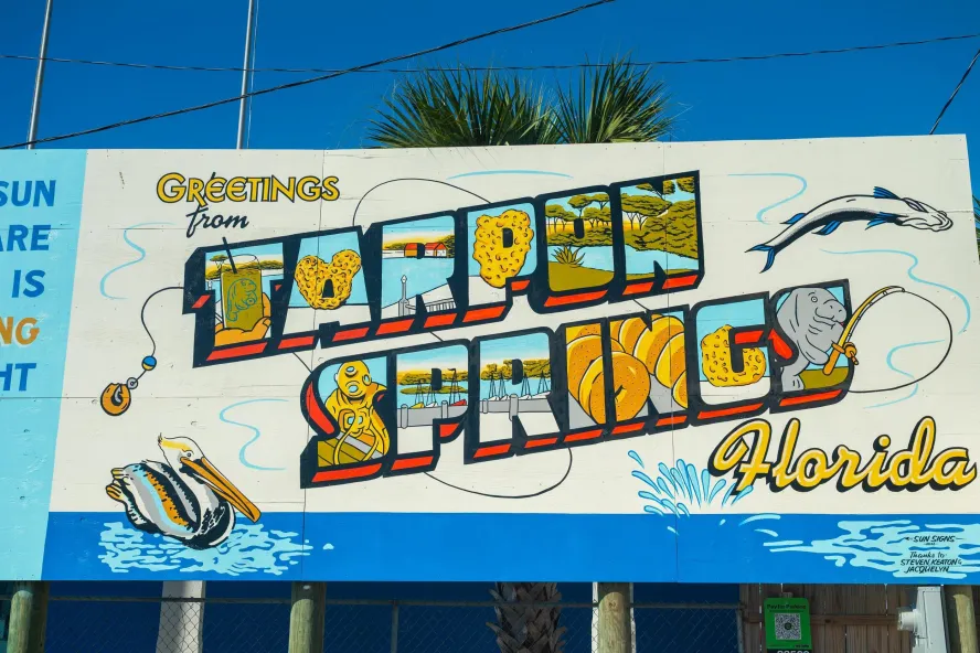 A colorful postcard-style mural reading "Greetings from Tarpon Springs, Florida"