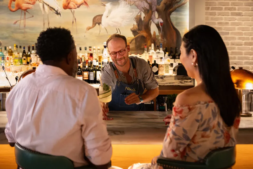 a bartender serves cocktails to a couple at Allelo in St. Pete
