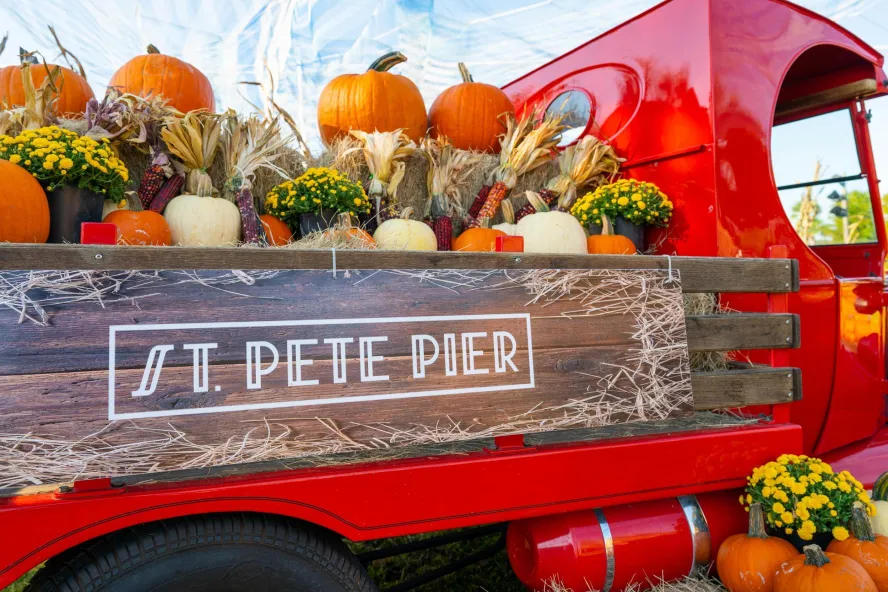a red truck piled high with pumpkins and gourds at the St. Pete Pier