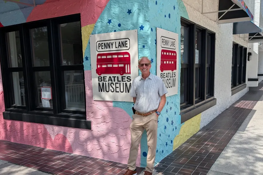 Dr. Robert, founder of the Penny Lane Beatles Museum, stands outside the museum's colorful exterior.