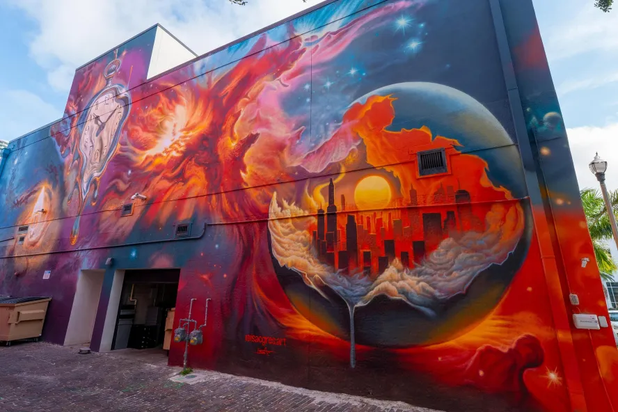 “The Taste of Creation” by artist Isac Gres, a surrealist mural featuring melting clocks, a glowing cityscape and cosmic imagery in downtown St. Pete.