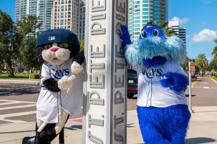 the rays mascots standing next to a sign at the St. Pete Pier