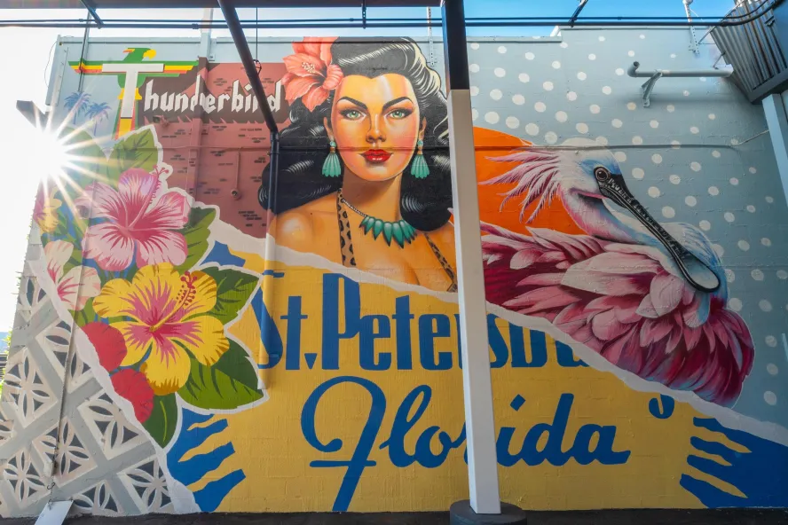 “Wish You Were Here” by the Vitale Brothers, a colorful St. Pete mural featuring a woman, tropical flowers and a roseate spoonbill.