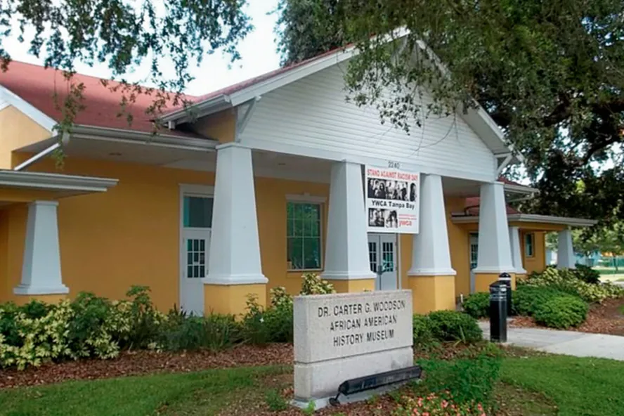 Exterior of the Dr. Carter G. Woodson African American History Museum in St. Petersburg, featuring a yellow building with white columns and a stone entrance sign.