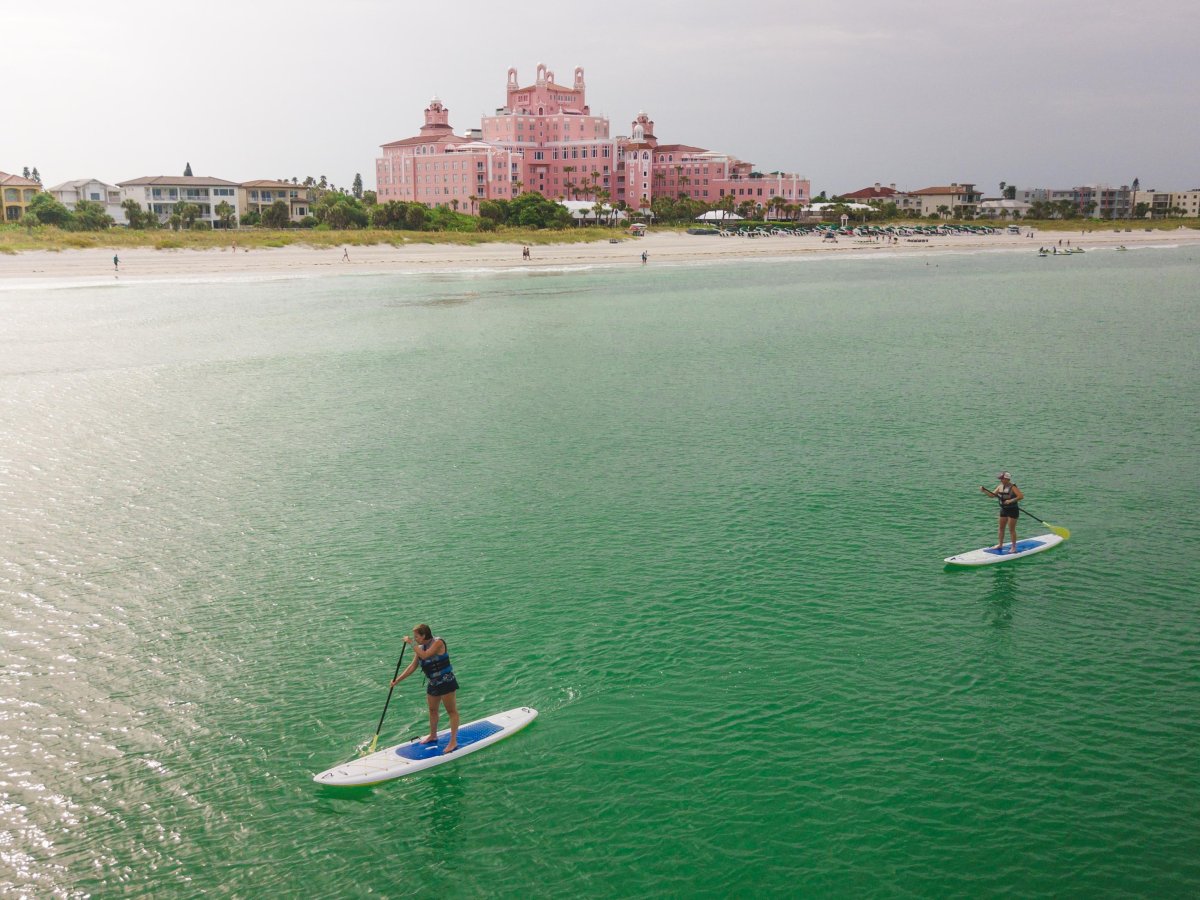 Two stand-up paddleboarders with the Don CeSar in the background
