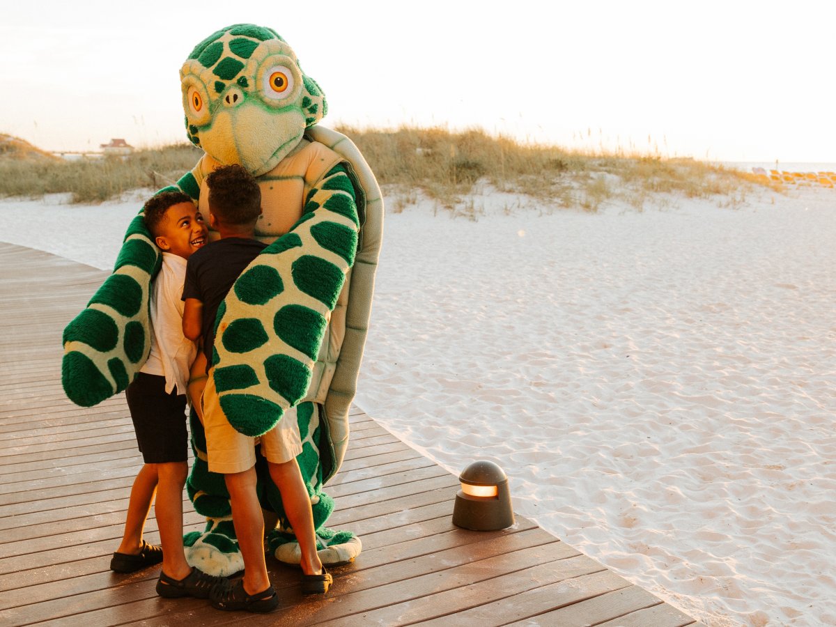 Person in turtle costume hugs two kids