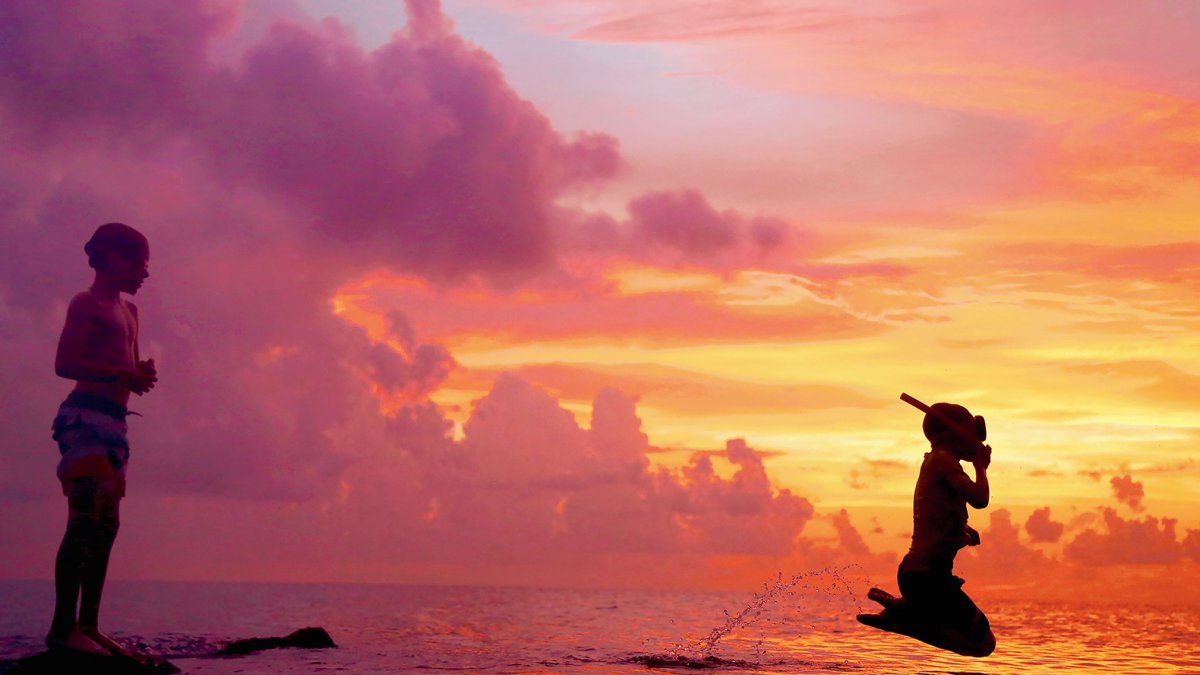 Schnorchler springt während eines wunderschönen Sonnenuntergangs auf Honeymoon Island in den Golf von Mexiko.