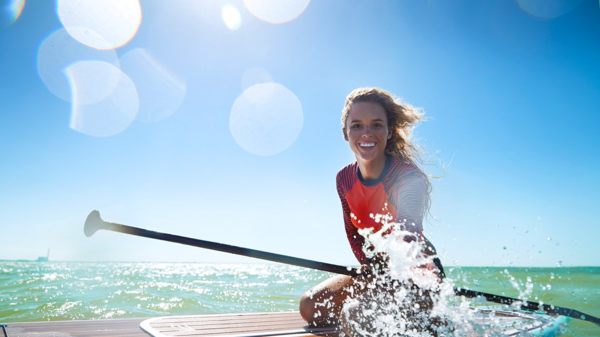 A young woman on a paddleboard splashes water in Anclote Key.