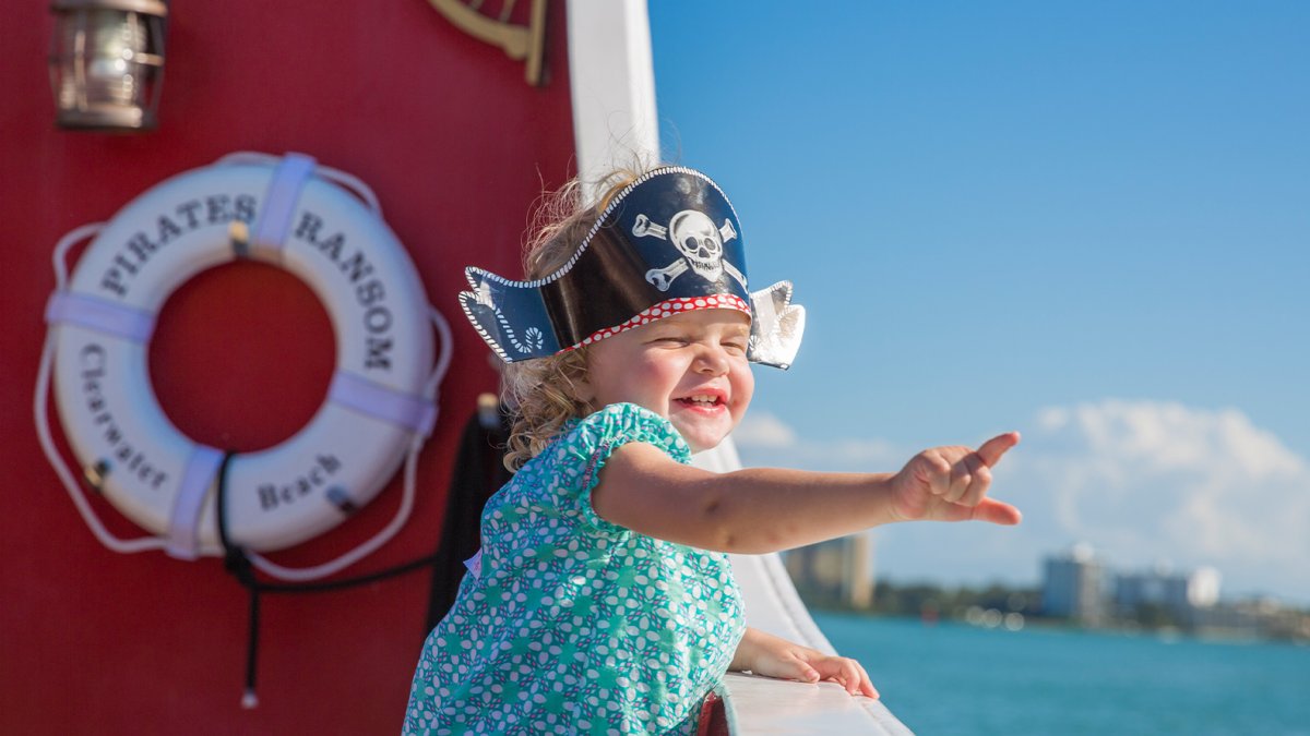 Uma garotinha feliz usando um chapéu de pirata a bordo do Cruzeiro Pirata do Capitão Memo.