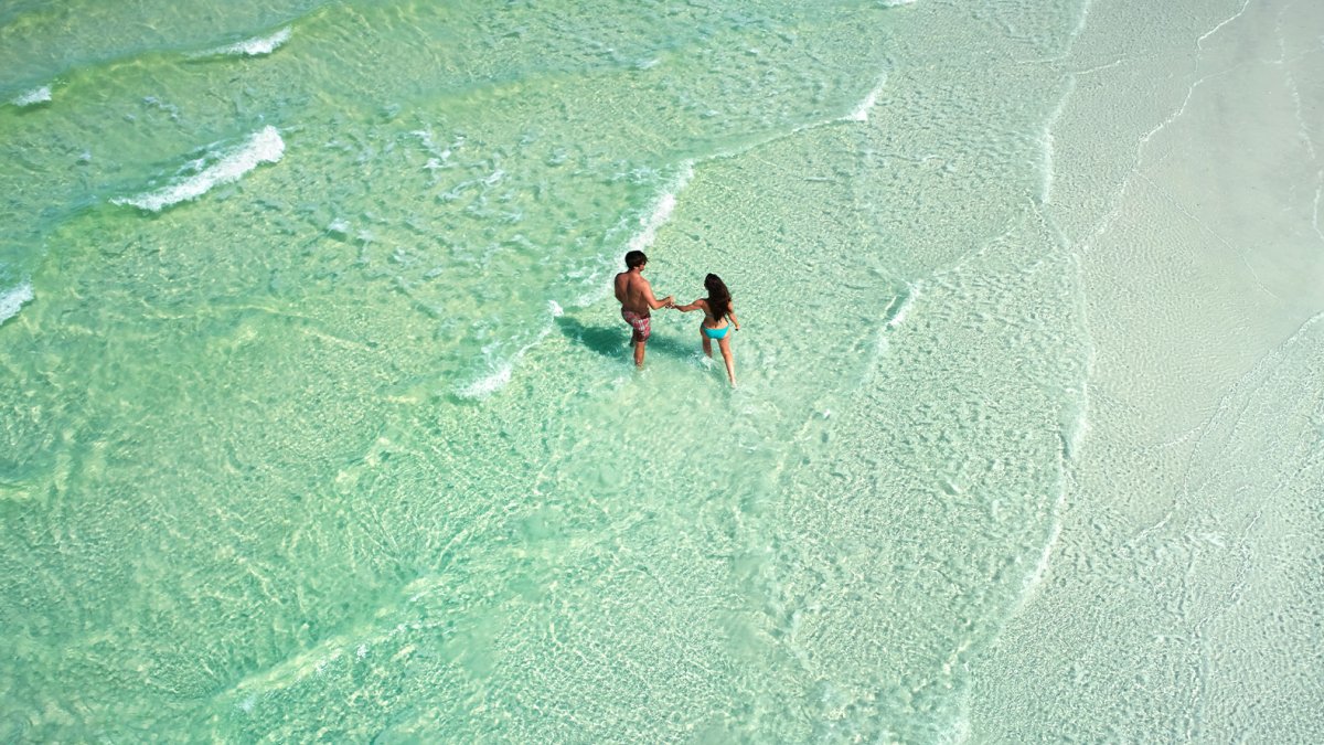 Una pareja paseando por las aguas verde esmeralda de Anclote Key