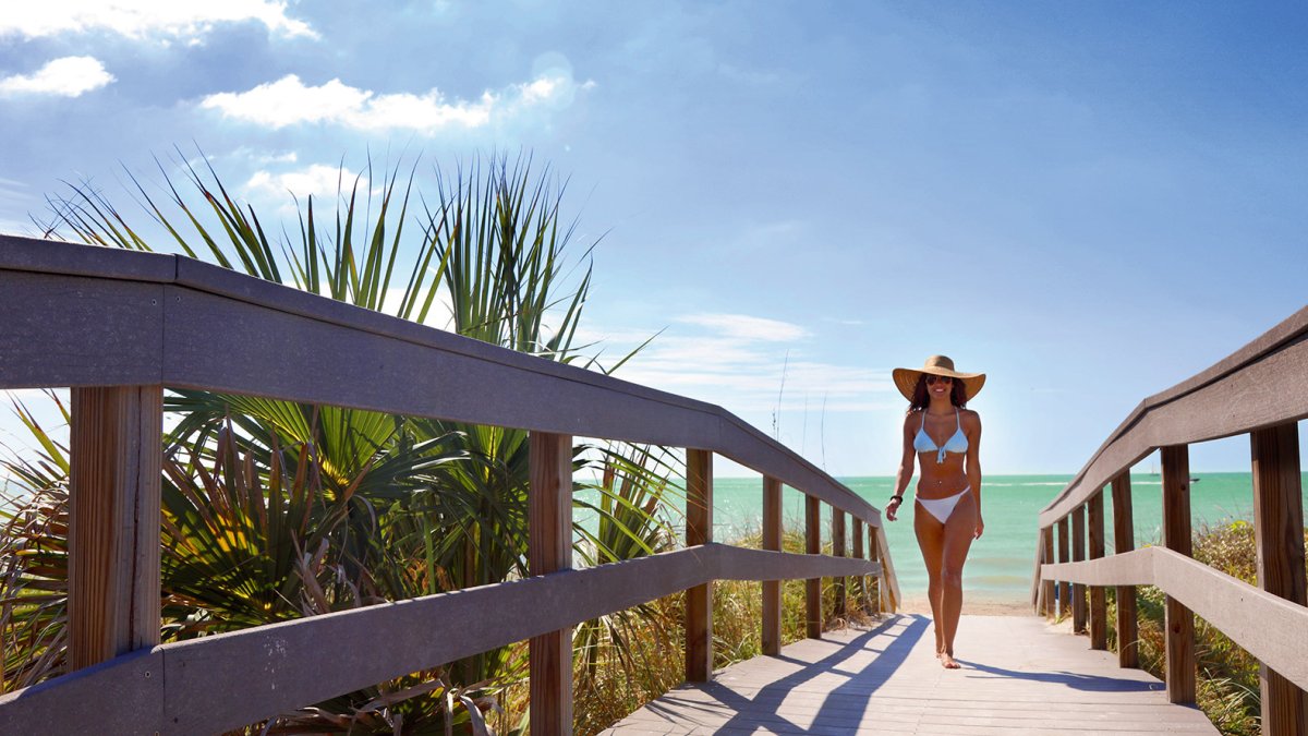 A young woman in white bikini walking off of Indian Rocks Beach.