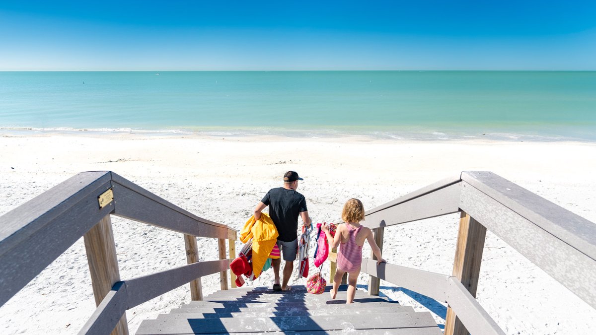 Eine Familie kommt über einen Holzsteg am Sunset Beach an.