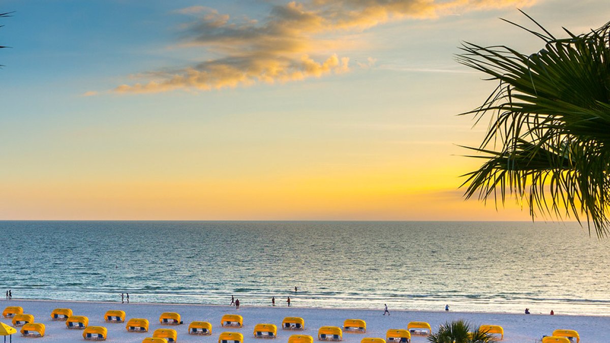 A view of sunset from a balcony at Alden Suites with yellow cabanas on a white sand beach