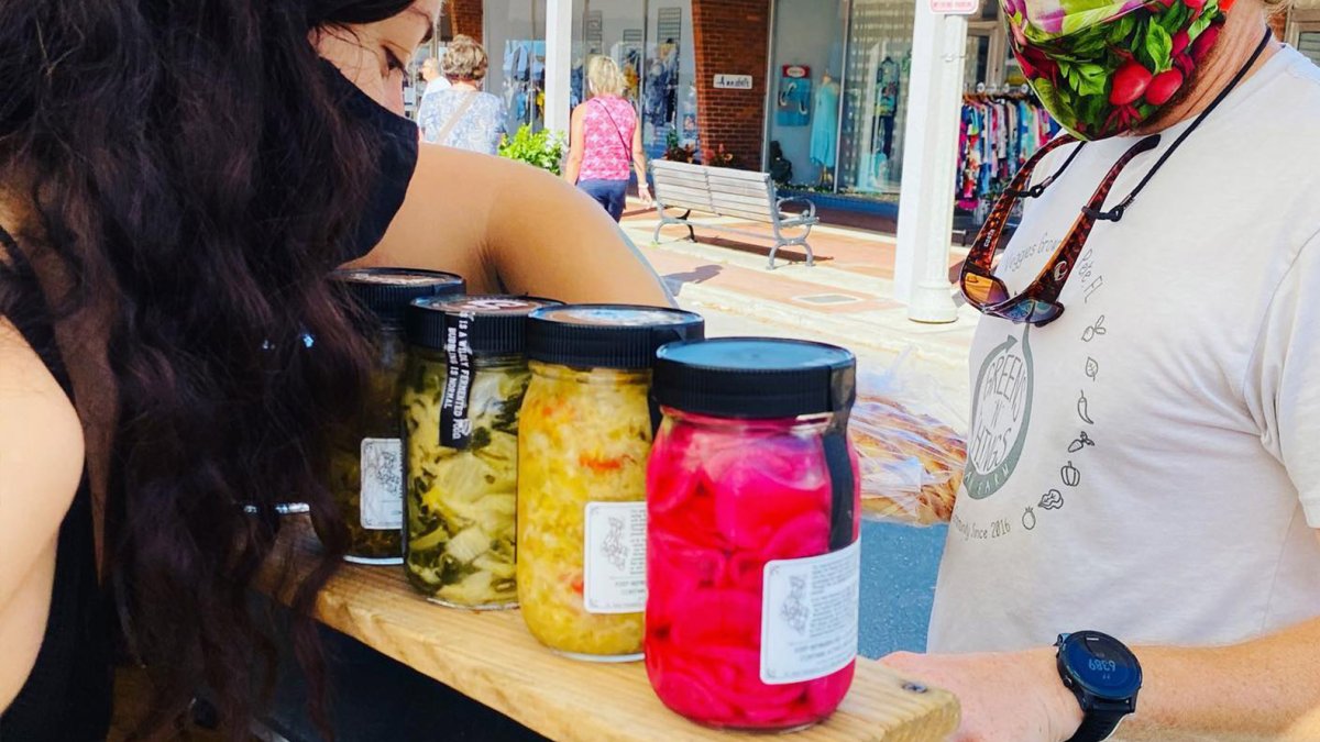 Eine Frau verkauft große Gläser mit eingelegtem Gemüse auf dem Corey Avenue Sunday Market in St. Pete Beach.