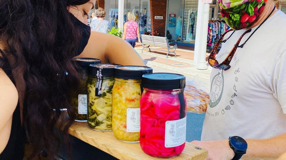 Una mujer vende frascos grandes de verduras en escabeche en el mercado dominical de Corey Avenue en St. Pete Beach.