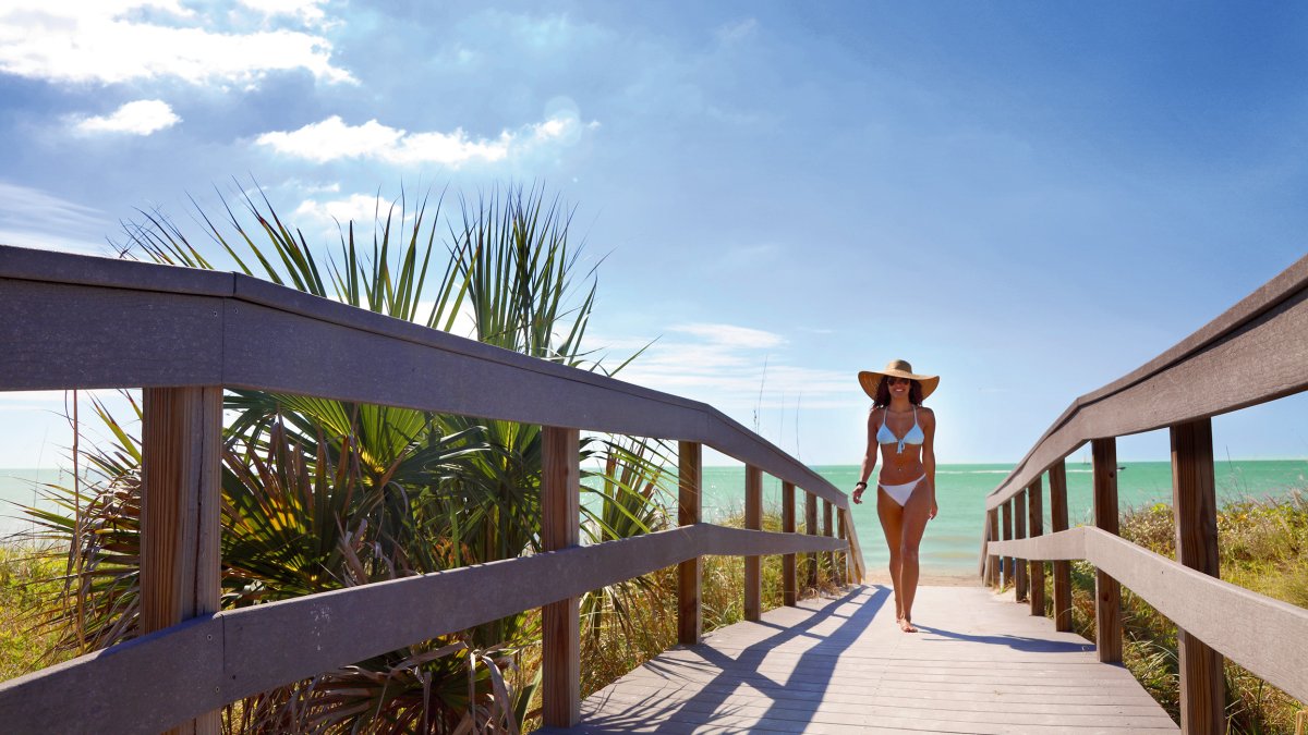 Uma jovem vestida de biquíni caminhando pelo calçadão de Indian Rocks Beach.