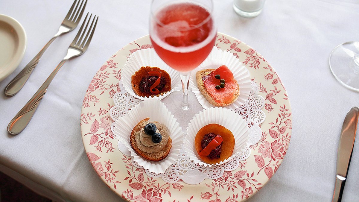 French canapes and a glass of red wine sit on top of a pink flowered plate at Cafe Largo in Largo, FL