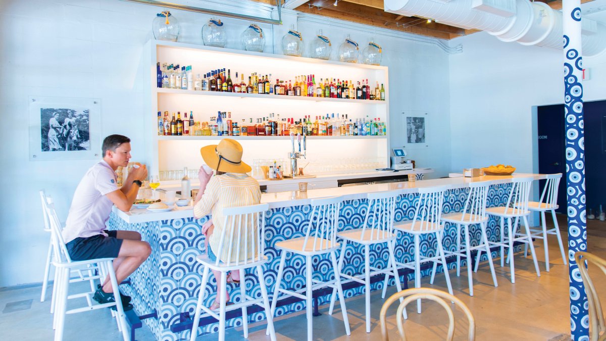 A couple enjoying a meal inside of the blue walls and chairs of Baba on Central restaurant.