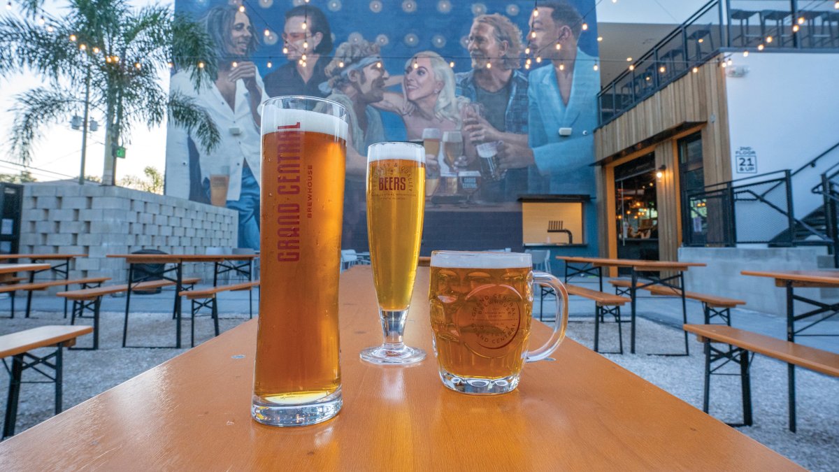 Three glasses of beer on top of an outside table in front of a large mural at the Grand Central Brewery in St. Pete.