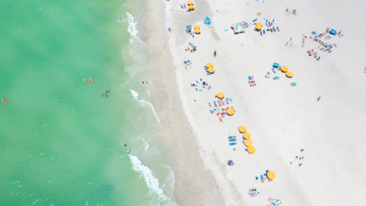 Aerial view of yellow beach cabanas and emerald-green waters of Treasure Island.