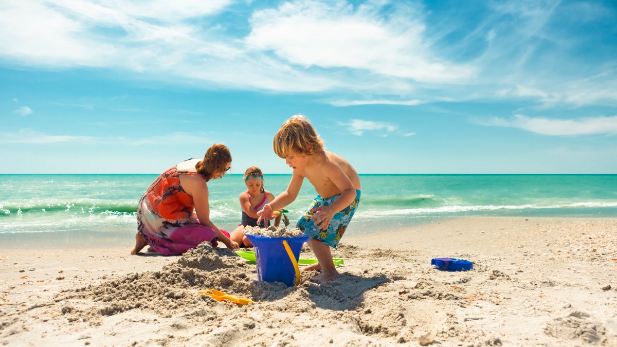 Eine Familie baut am Strand von Treasure Island eine Sandburg.