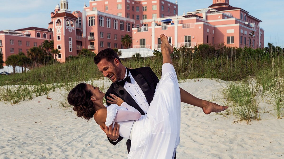 A groom sweeps up his bride in front of the Don CeSar