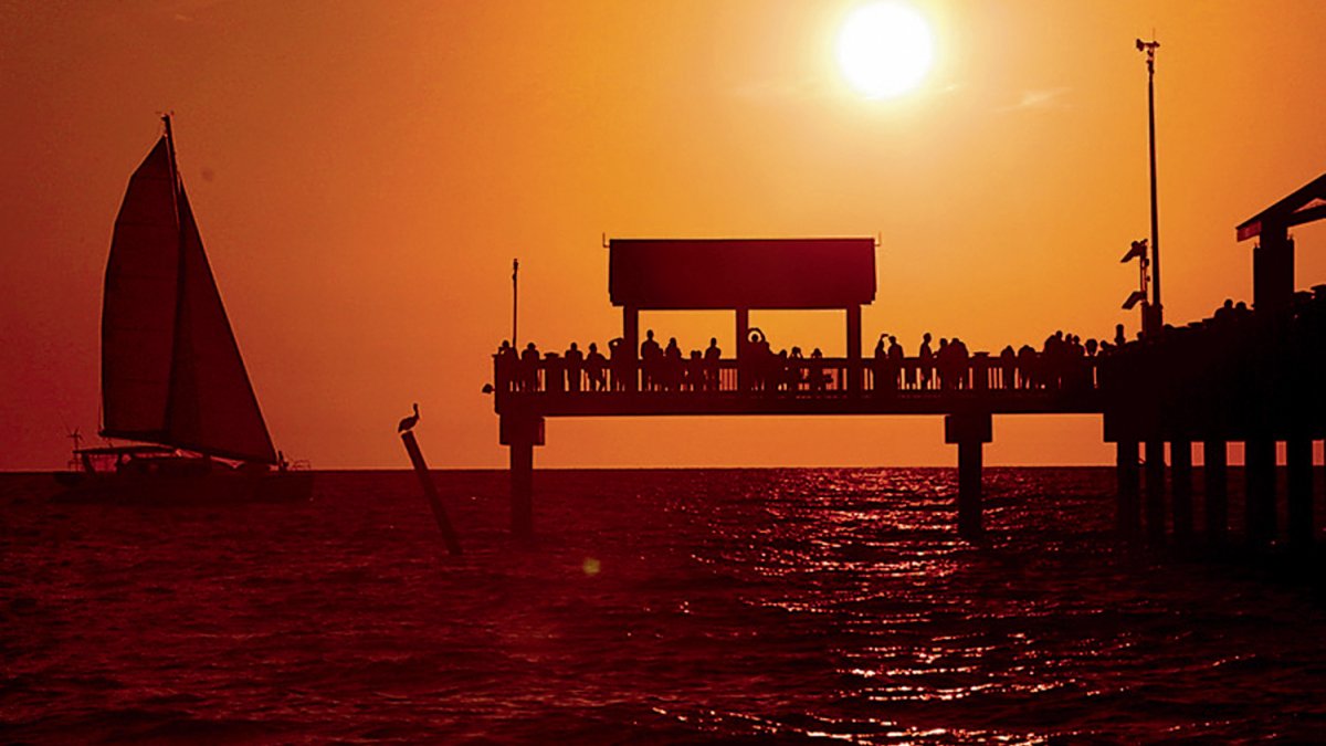 Pier 60 ao pôr do sol com um barco à vela na água