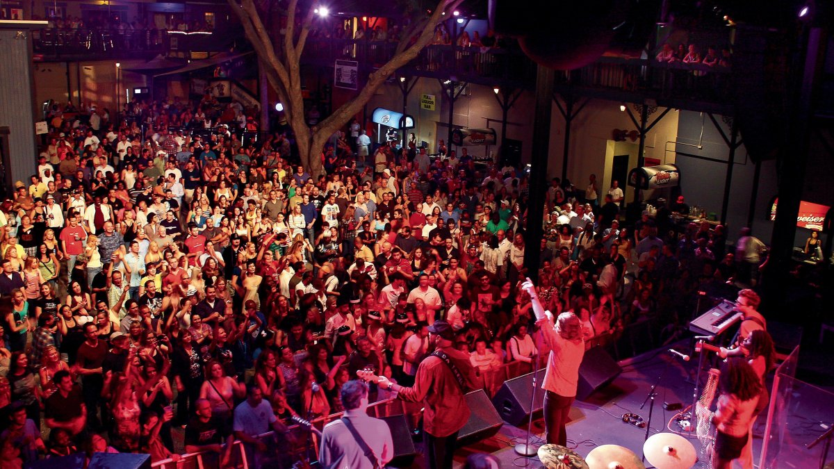 A band plays in front of a tightly packed crowd of people at Jannus Live