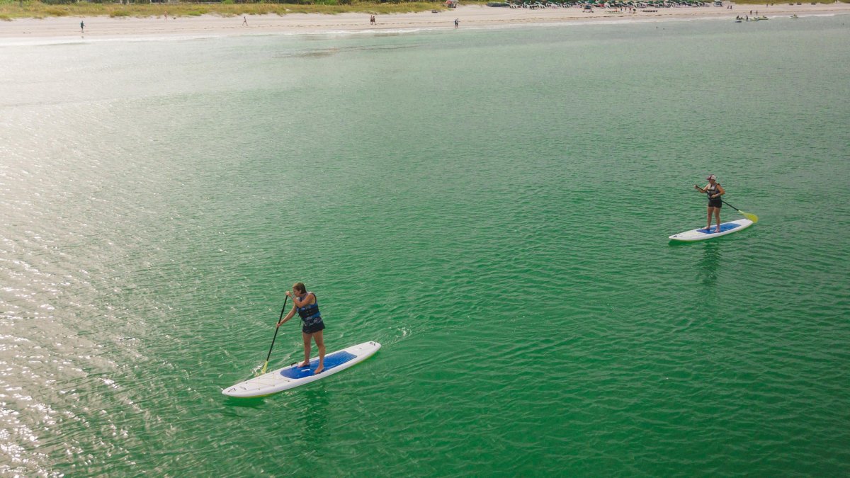 Two stand-up paddleboarders with the Don CeSar in the background