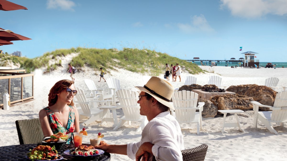 Um casal desfruta de coquetéis na praia no Tate Island Grill no Sandpearl Resort