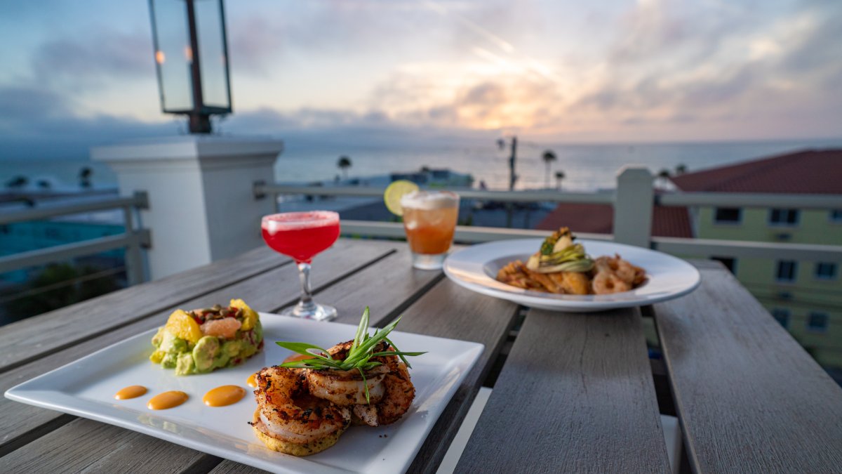 Two dishes on a table at the rooftop of The Dewey overlooking sunset at Pass-A-Grille