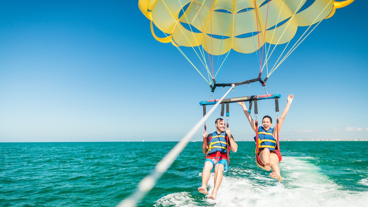 A couple taking flight in a parasail in Clearwater Beach.