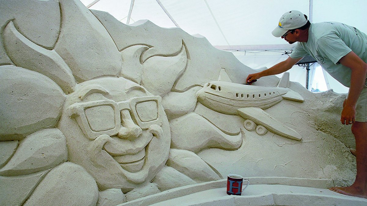 Um homem terminando uma escultura do sol usando óculos escuros.