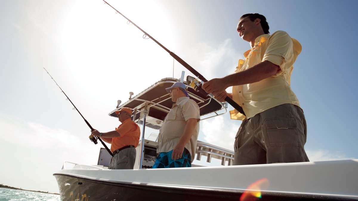 A group of men in a black boat fishing.