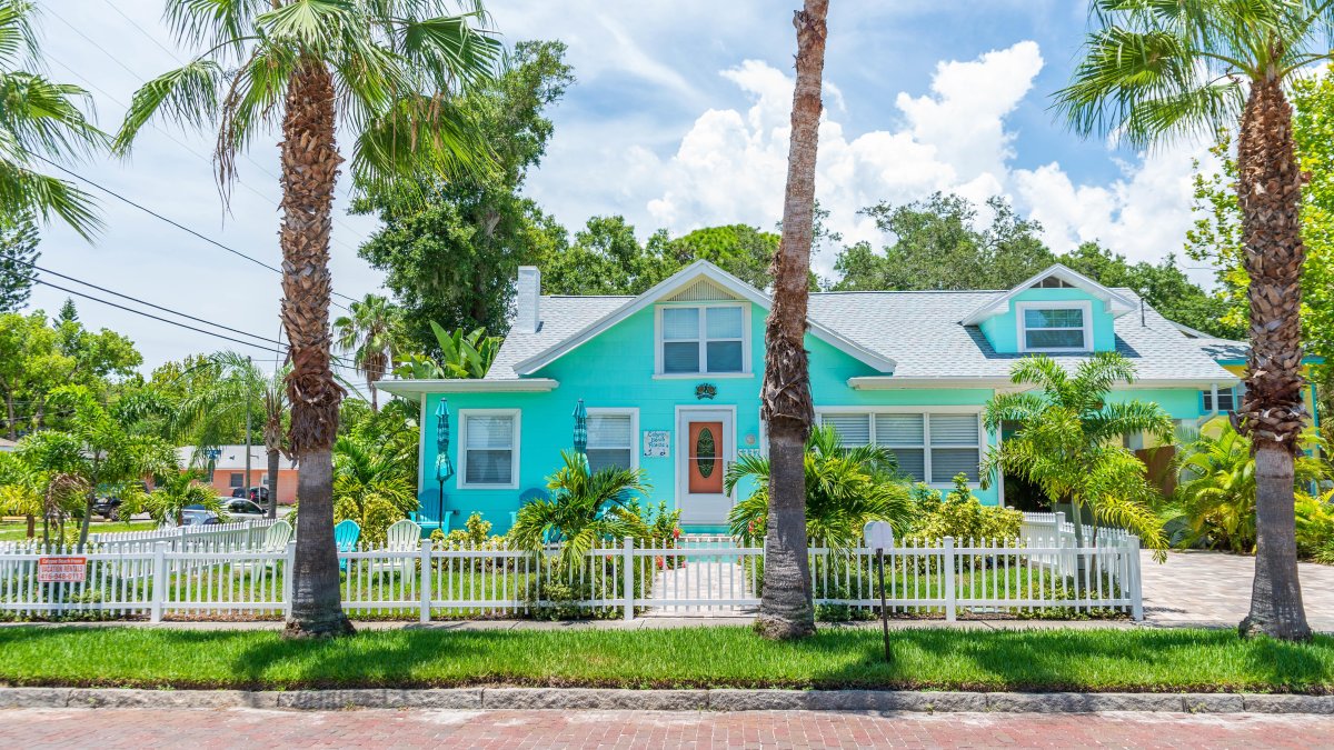 Ein blaues Haus mit Palmen drumherum, von der Straße in Gulfport aus gesehen.