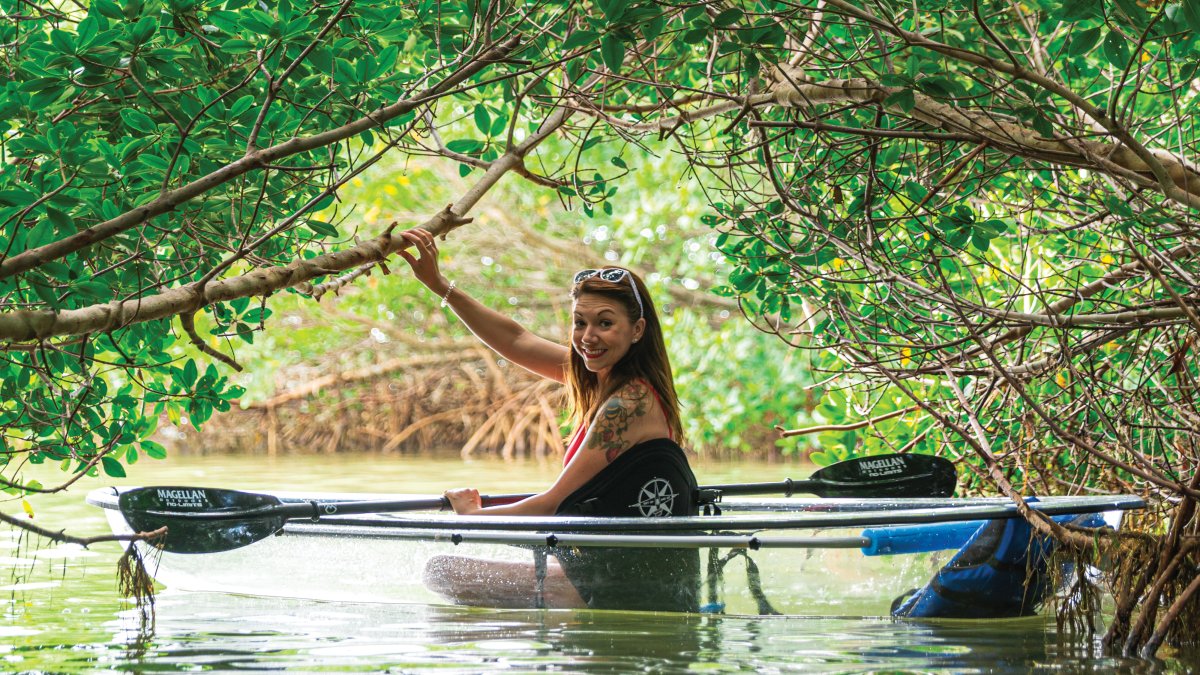 Uma senhora atravessando as árvores de mangue em um caiaque transparente perto da Shell Key Preserve.