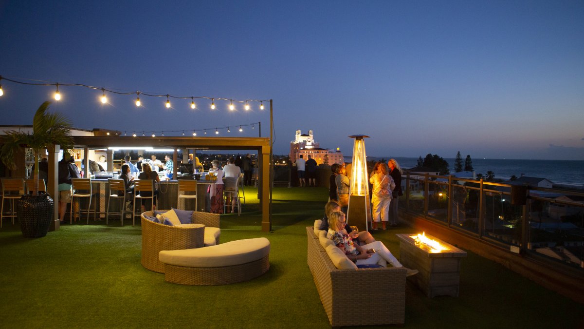 Overview of rooftop bar at Hotel Zamora at dusk showing people enjoying drinks by the fireplace.