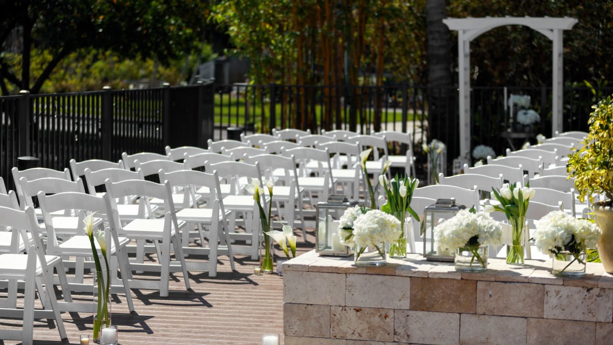 An outdoor wedding setting with chairs, an arch and white flowers decorating at Hotel Zamora. the entrance.