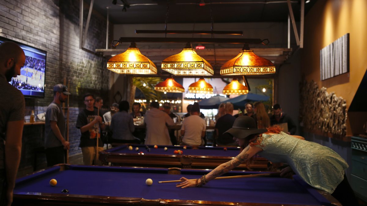 Um casal jogando sinuca em um bar durante a noite.