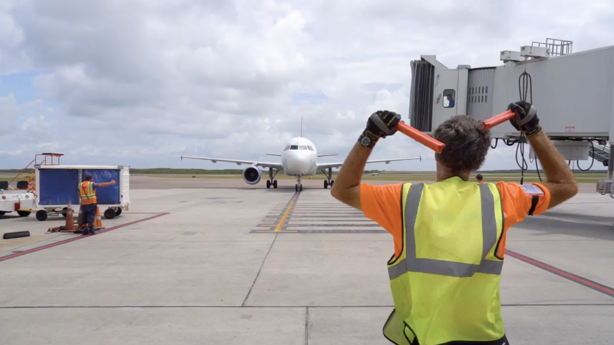 A flag person helping airplane taxing at airport