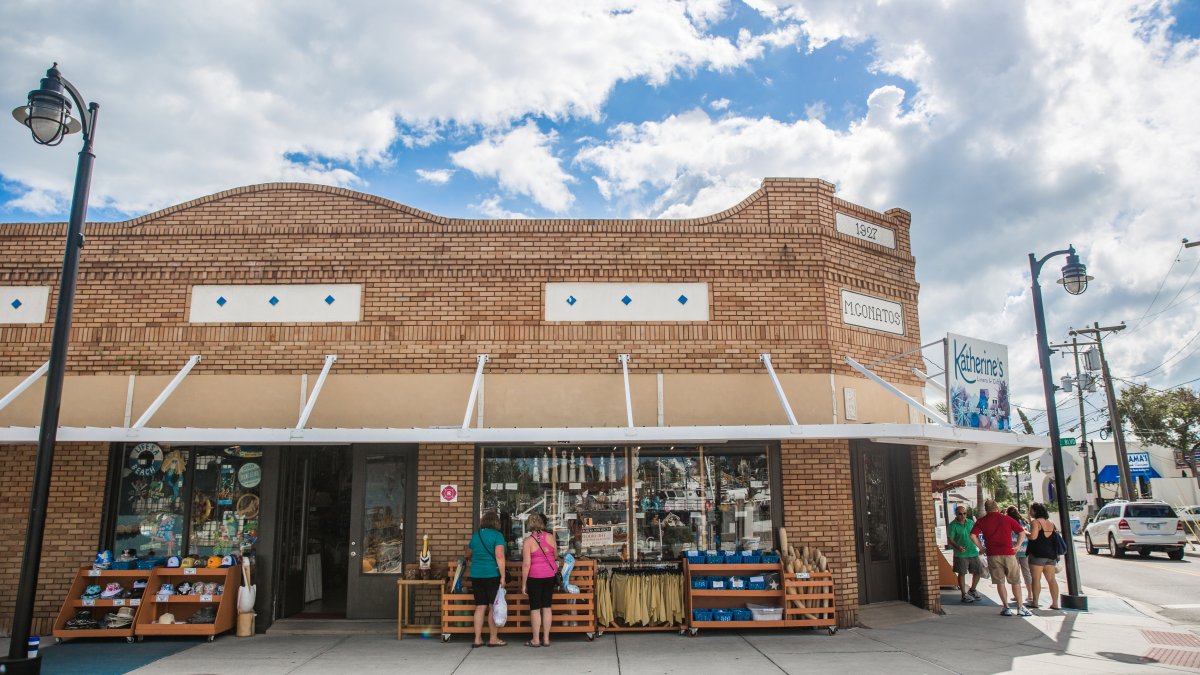 The Mconatos store brick front with lots of merchandising on display and some people shopping