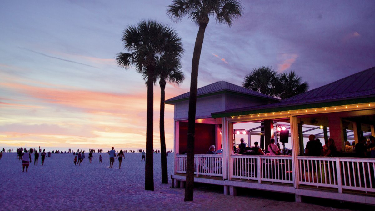 After Sunset view of the beach and Crabby's Beachside Pavilion with palm trees on the beach with a beautiful colorful sky.