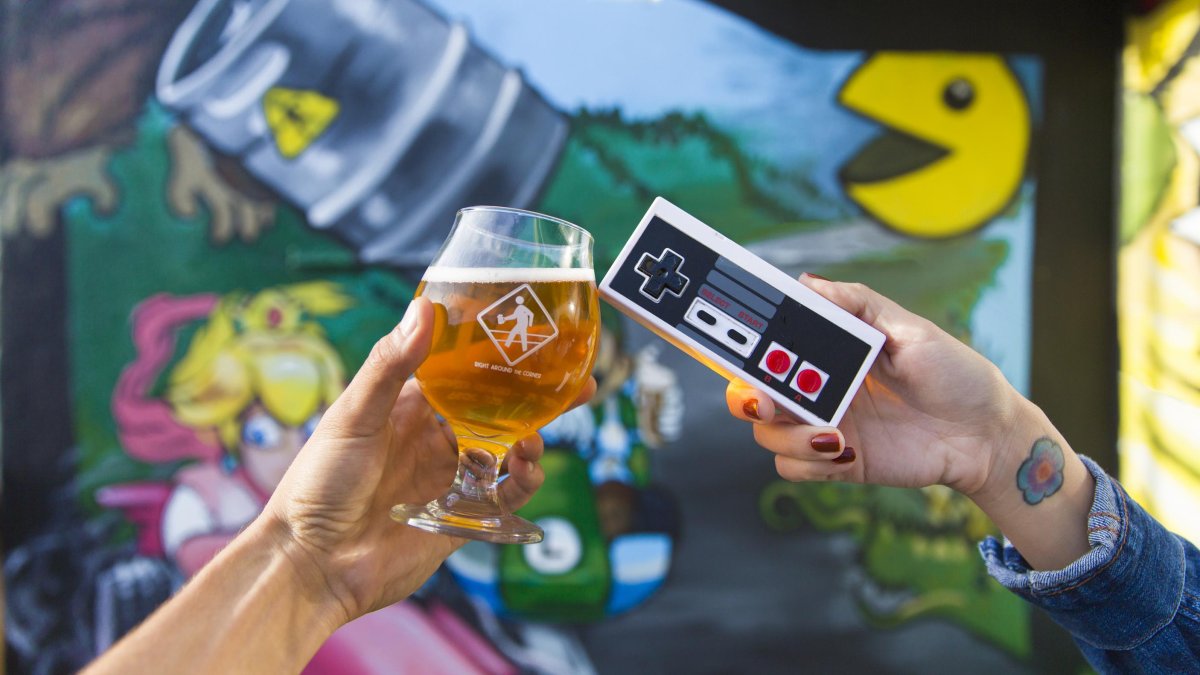 People Cheers a beer and a game controller outside the brewery Right Around the Corner in downtown St. Pete