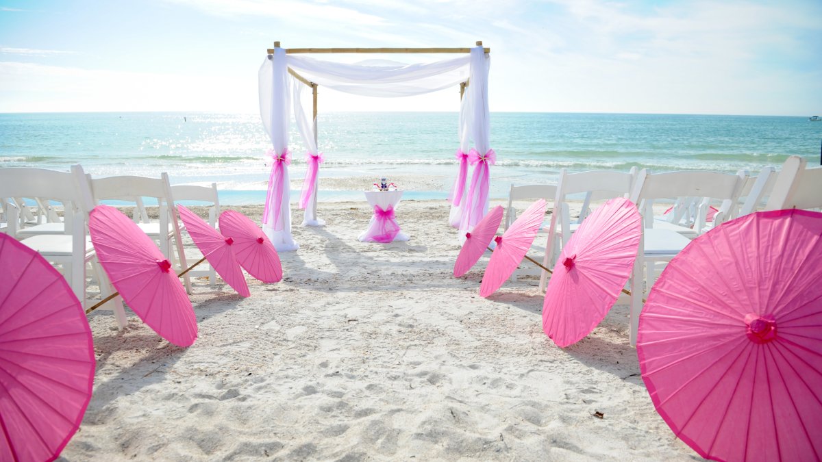 A wedding with umbrellas set up on the beach