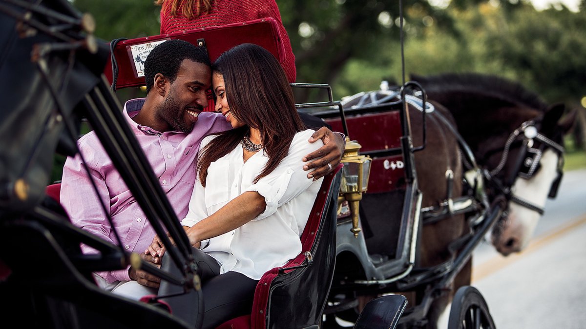 An African-American couple looking closely to each other while riding a carriage.