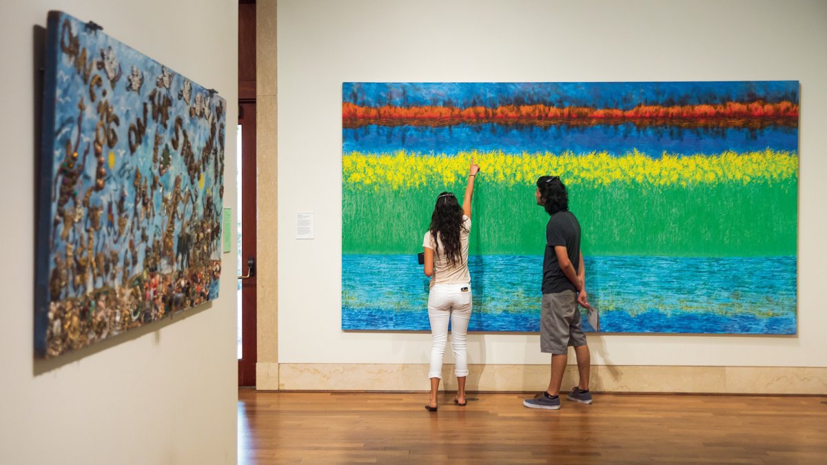 Ein Paar schaut sich ein Gemälde im St. Pete Museum of Fine Arts genau an.