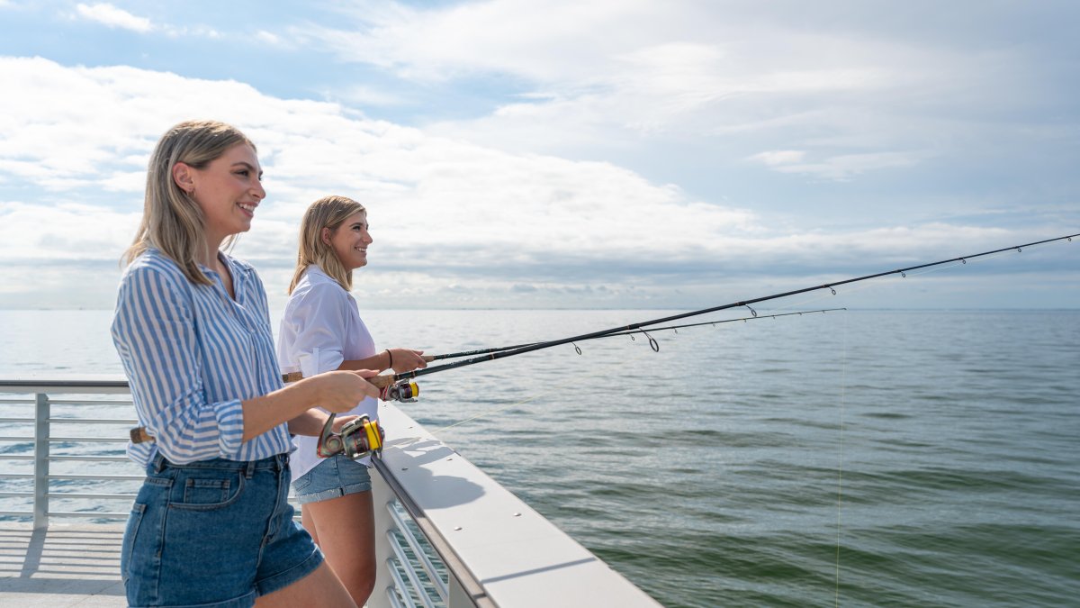 Two caucasian young ladies fishing off of St. Pete Pier.